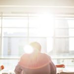 man sitting on chair in front on window during daytime
